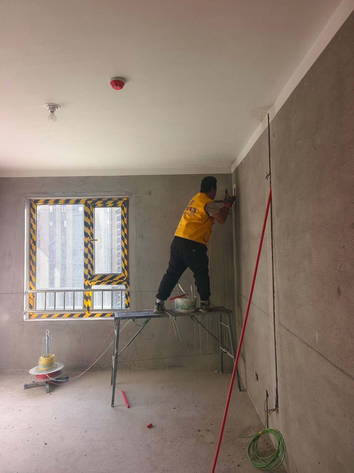 都市庭院工地：墙面开槽布线，窗框已做成品保护